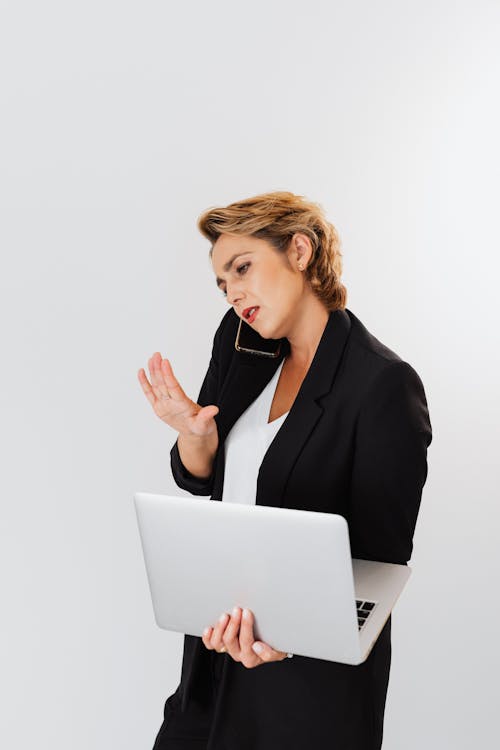 Woman Talking on the Phone While Holding Laptop