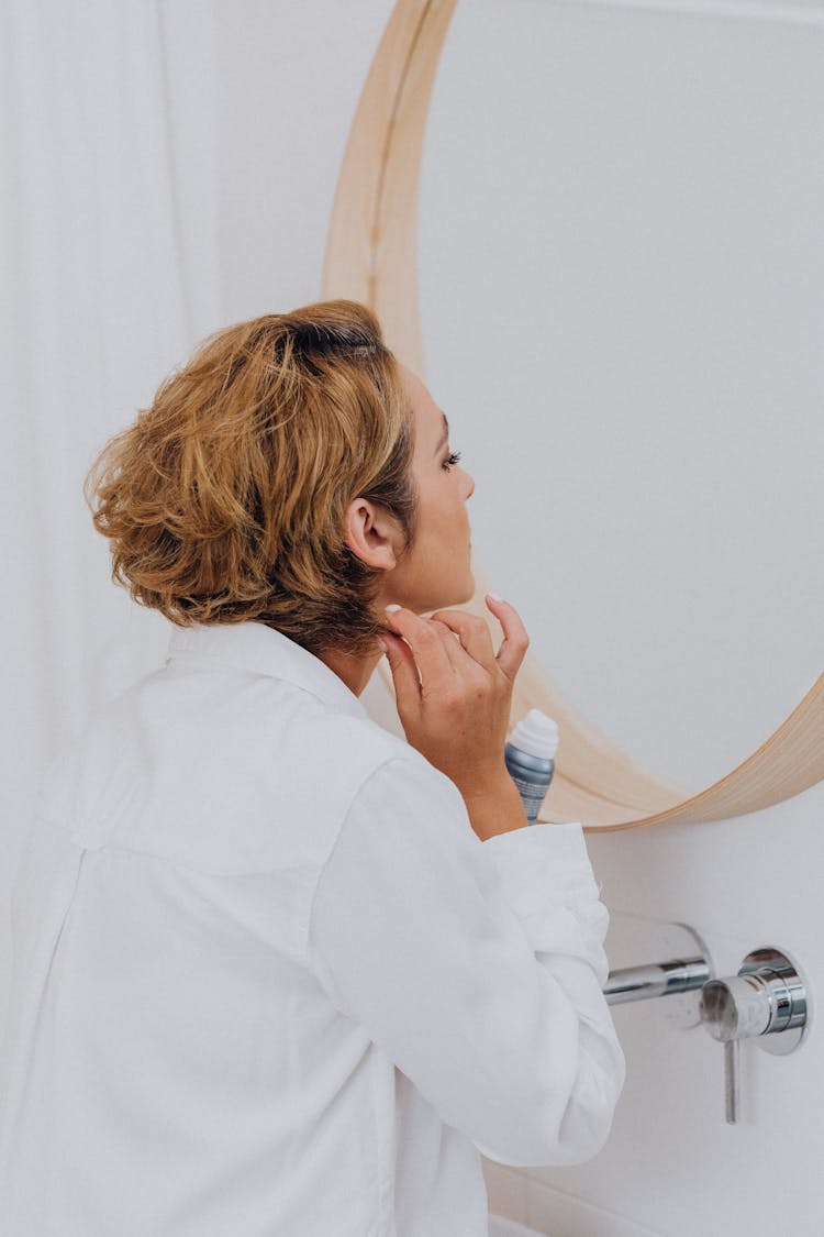 Woman Looking At Herself In A Bathroom Mirror 