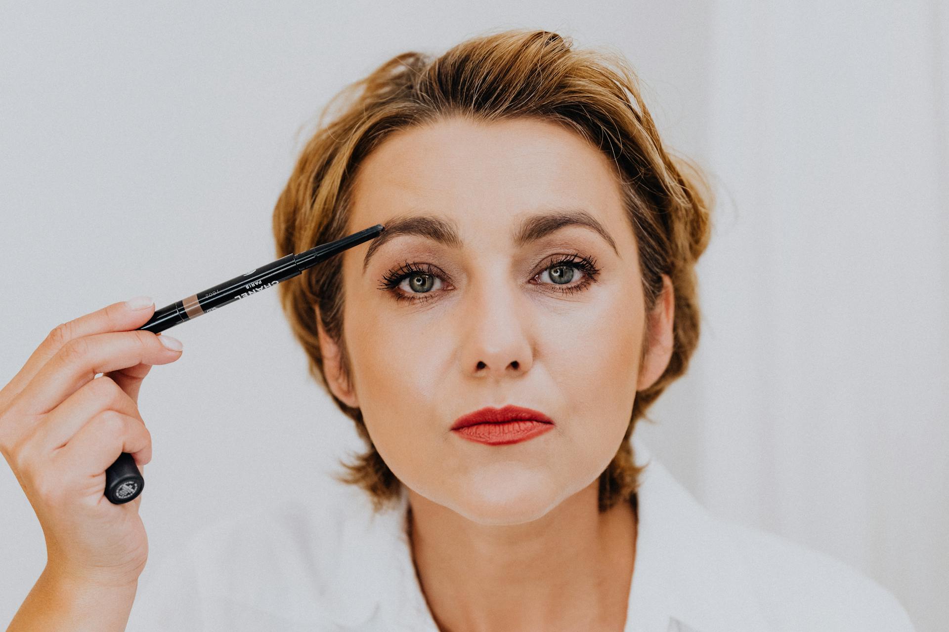 Woman in White Shirt Holding Eyebrow Liner