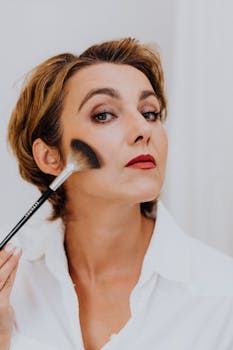 Elegant woman applying makeup with a brush, showcasing confidence and style.