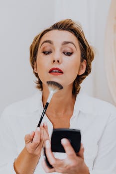 Close-up of a woman elegantly applying makeup using a brush with precision.