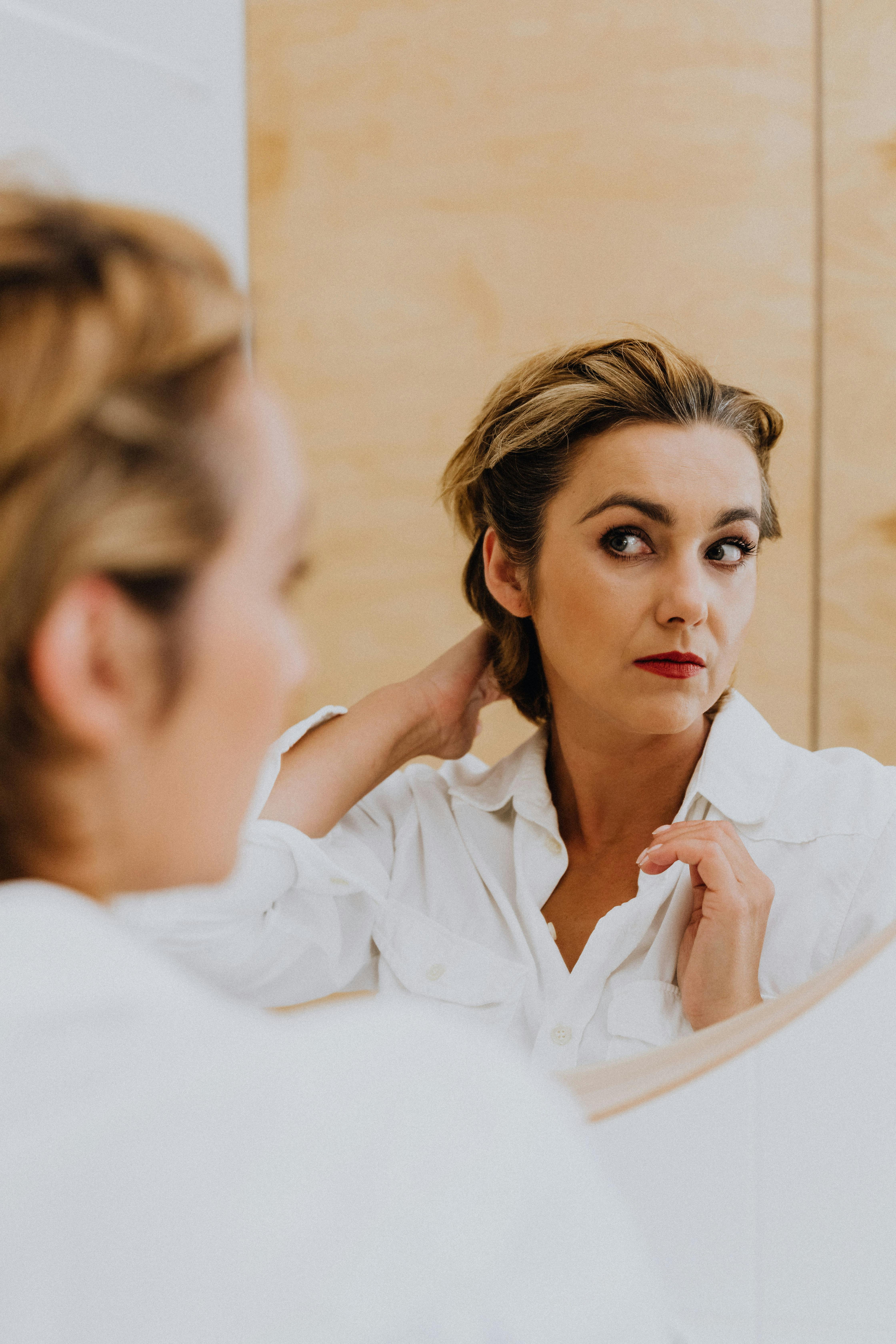 woman in white long sleeve shirt in front of the mirror