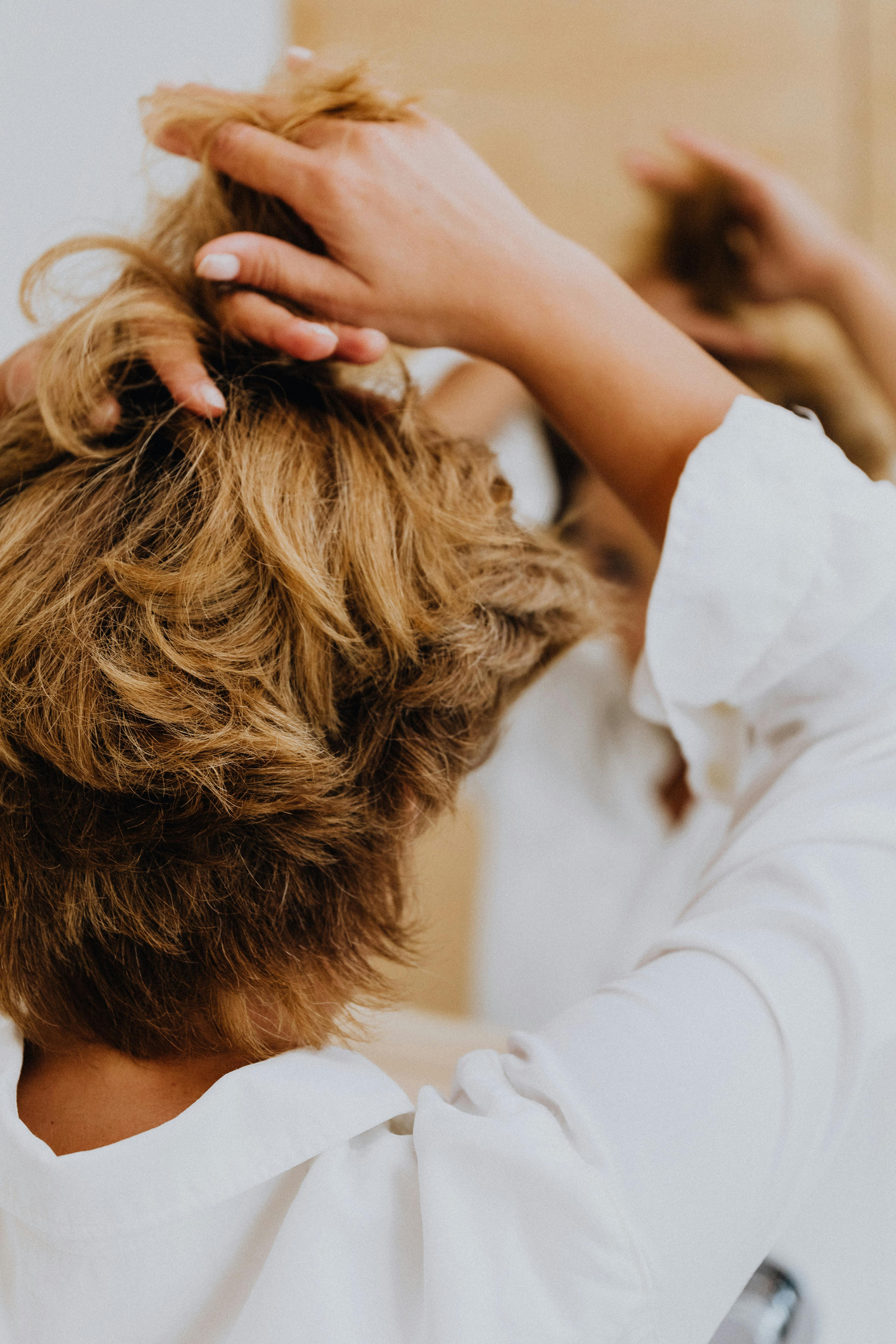 woman in white long sleeve shirt holding her hair