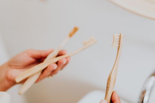 Close-up of hands holding bamboo toothbrushes, promoting sustainable dental care.