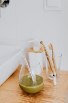 A close-up of a green smoothie in a bathroom with eco-friendly toothbrushes.