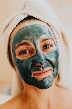 A woman enjoying a relaxing facial treatment with a green mask applied.