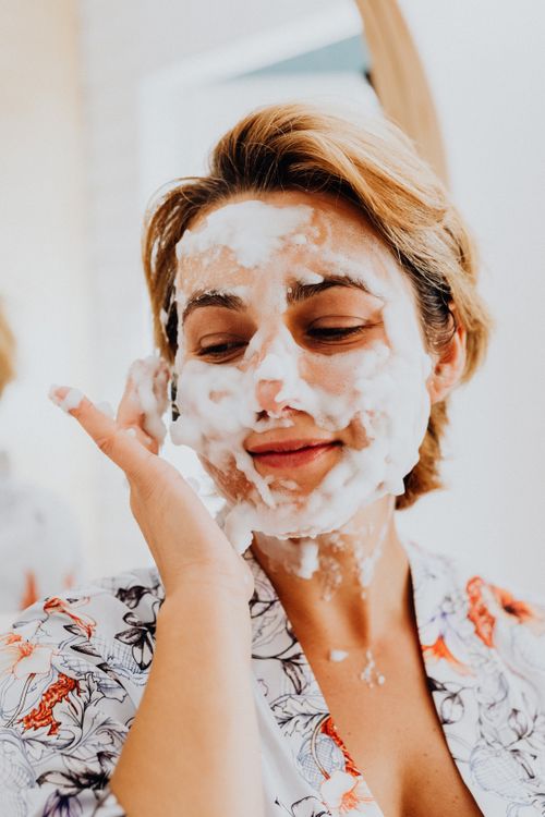 Free Adult woman applying a fluffy foam mask, promoting relaxation and skincare. Stock Photo