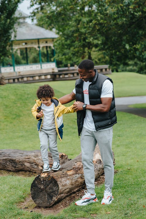 Black father supporting son on log