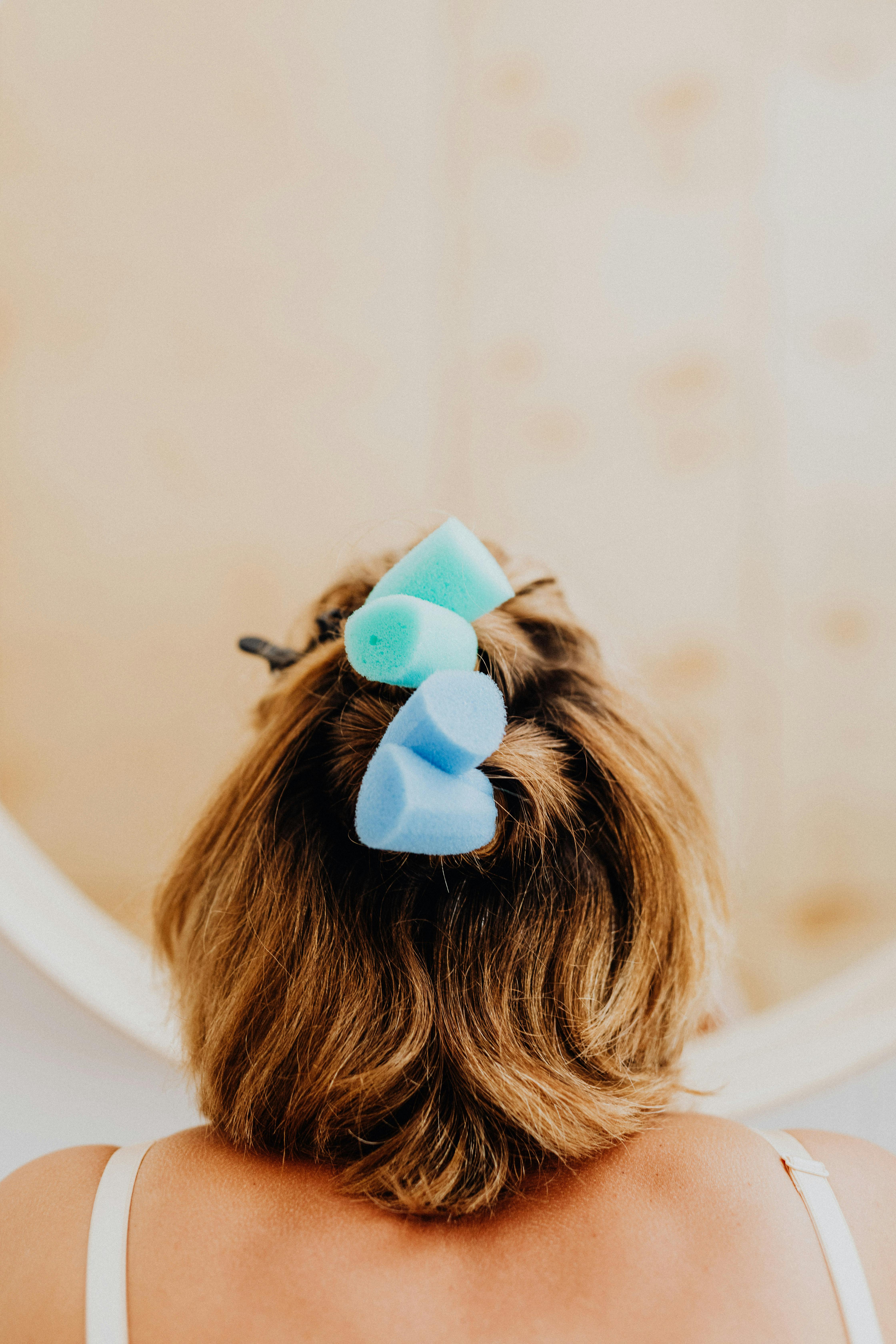 Back view of a woman with hair curlers, focusing on self-care and hairstyle preparation.