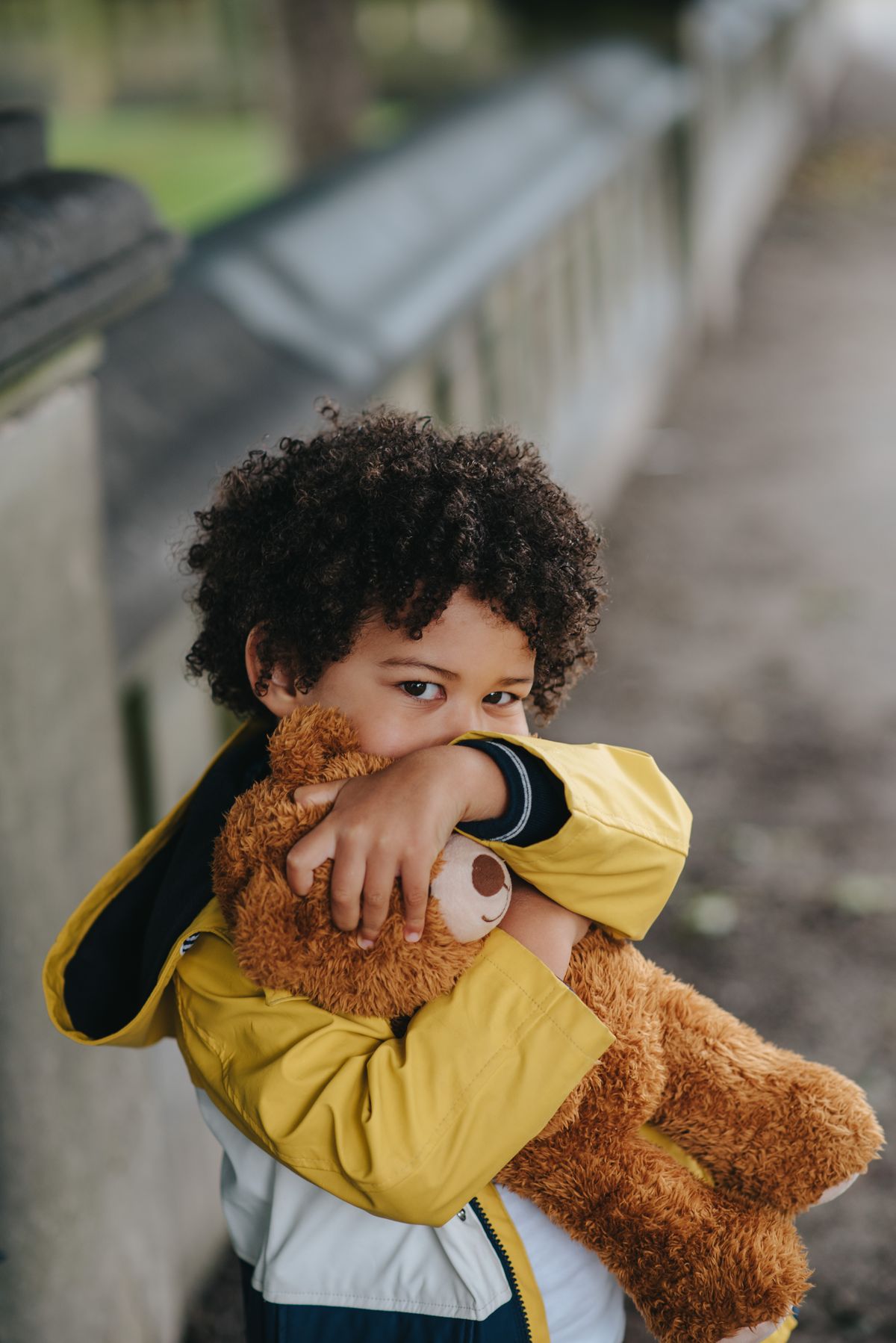Curly-haired child hugging a teddy bear