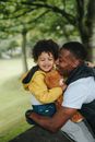 Black father embracing son in park