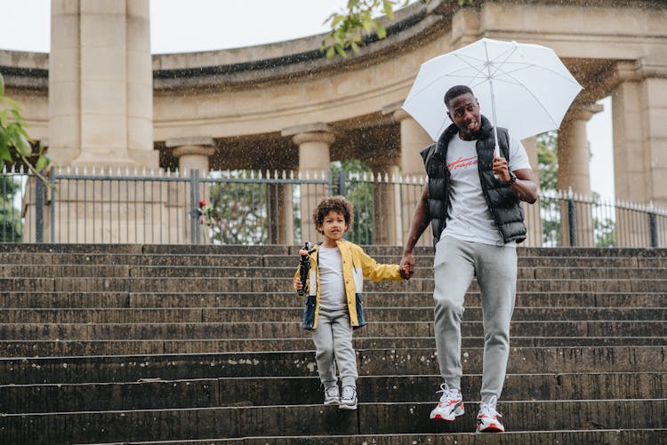 Black Son And Father On Stairs Under Rain