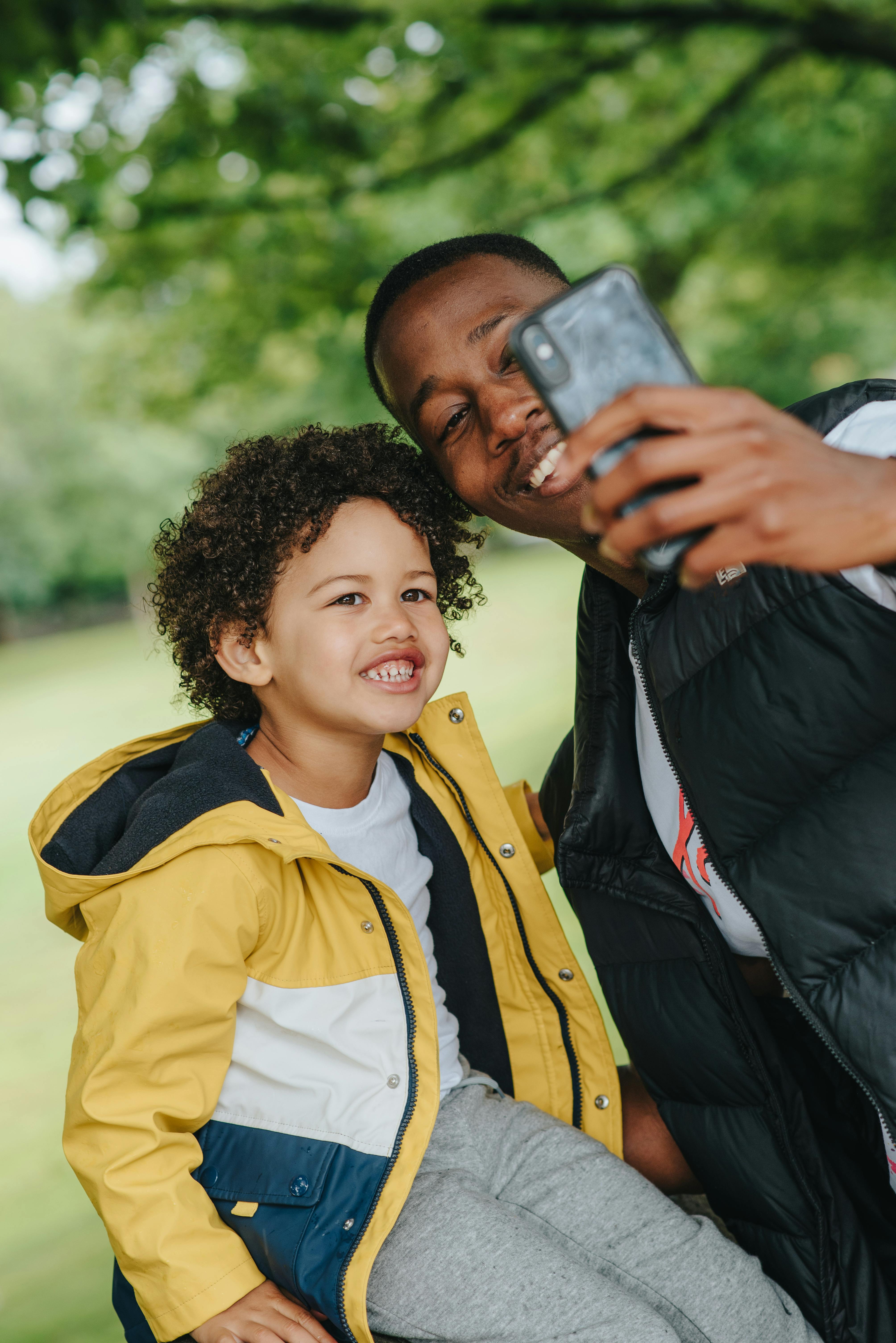 content black man with son taking self portrait on smartphone