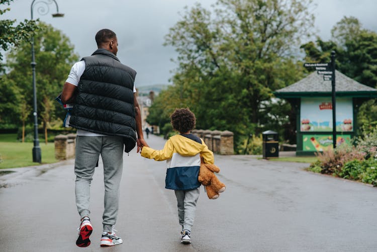 Unrecognizable Black Father With Son Holding Hands On City Road