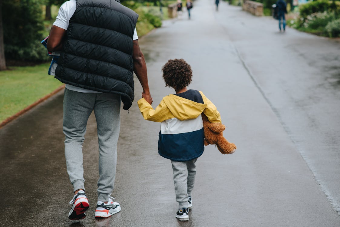 Man in Black Bubble Jacket Carrying Child in Yellow Jacket