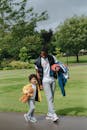 Black man with happy boy walking on road near park