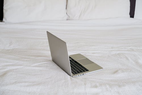 Modern laptop on creased bed cover in house