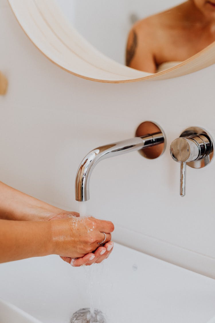 Close-up Of Person Washing Hands Under Faucet