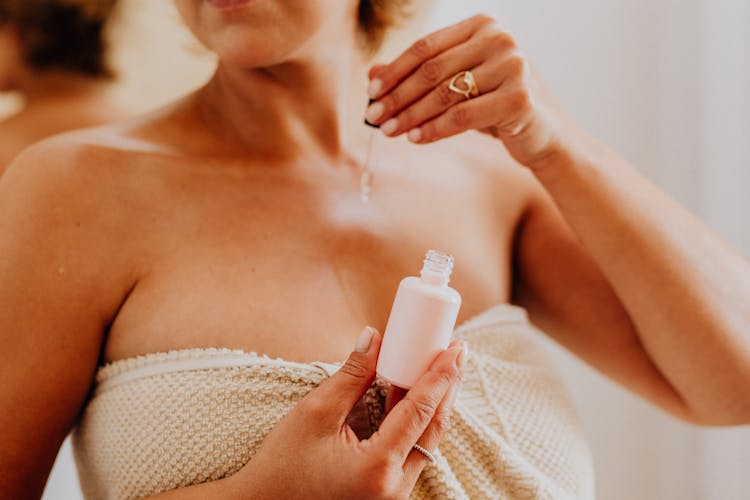 Close-up Of Woman Applying Serum On Body