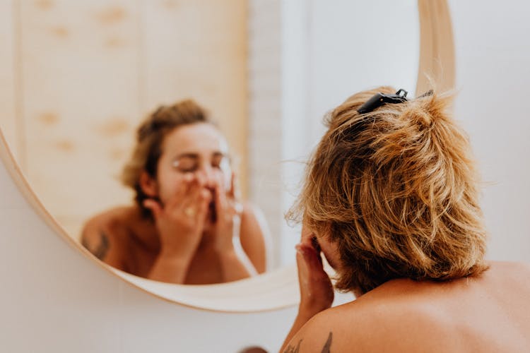 Woman Washing Face In Mirror