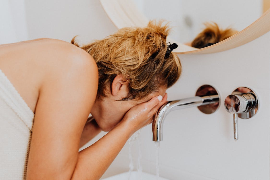 Free Woman Washing Face in Bathroom Stock Photo