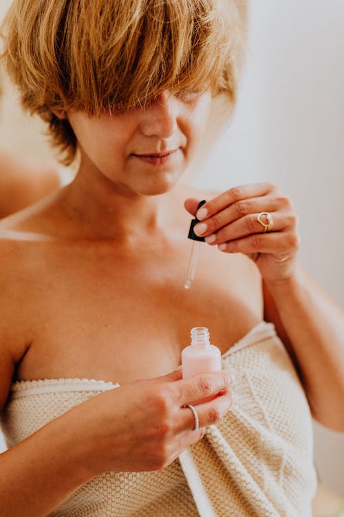 Woman Wrapped in Towel Using Moisturizer 