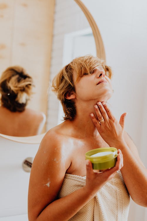 Topless Woman Applying a Skin Care Product on Neck