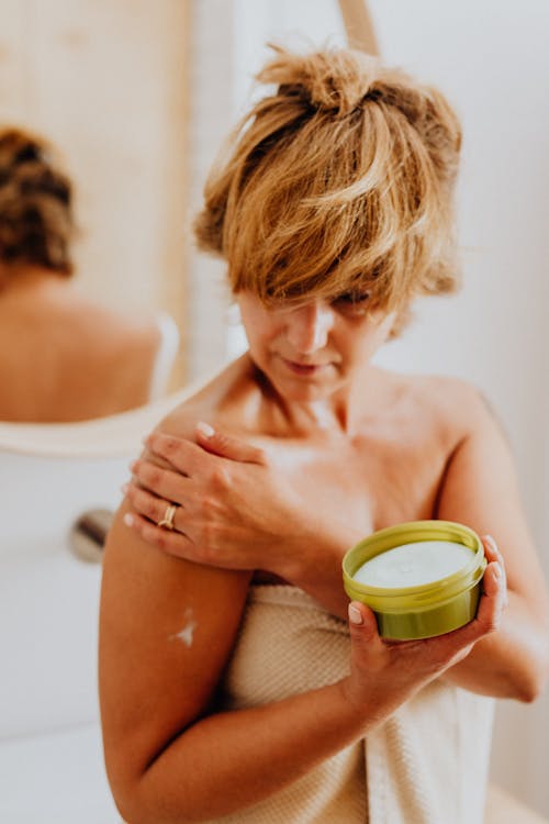 Topless Woman Applying Skin Care Product on Body