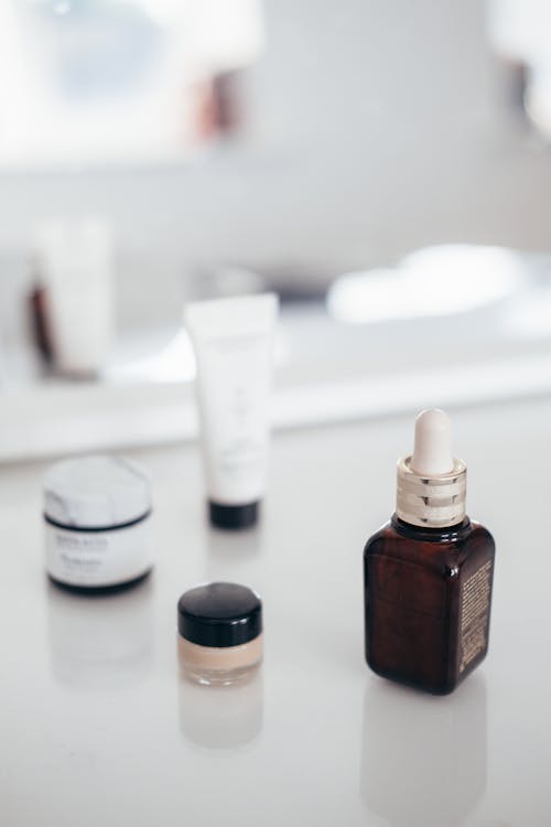 Collection of beauty products on table reflecting in mirror