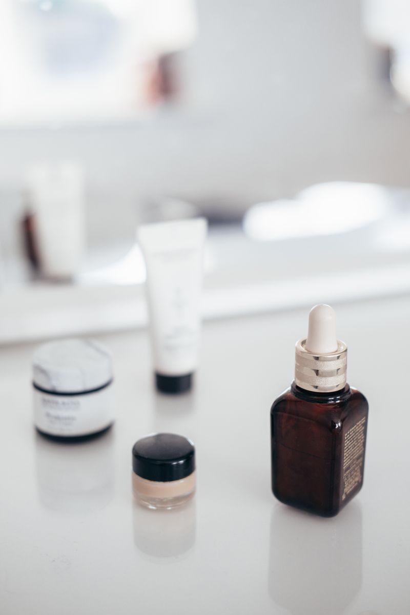 A collection of cream jars, a lotion tube and an oil bottle arranged on a light surface