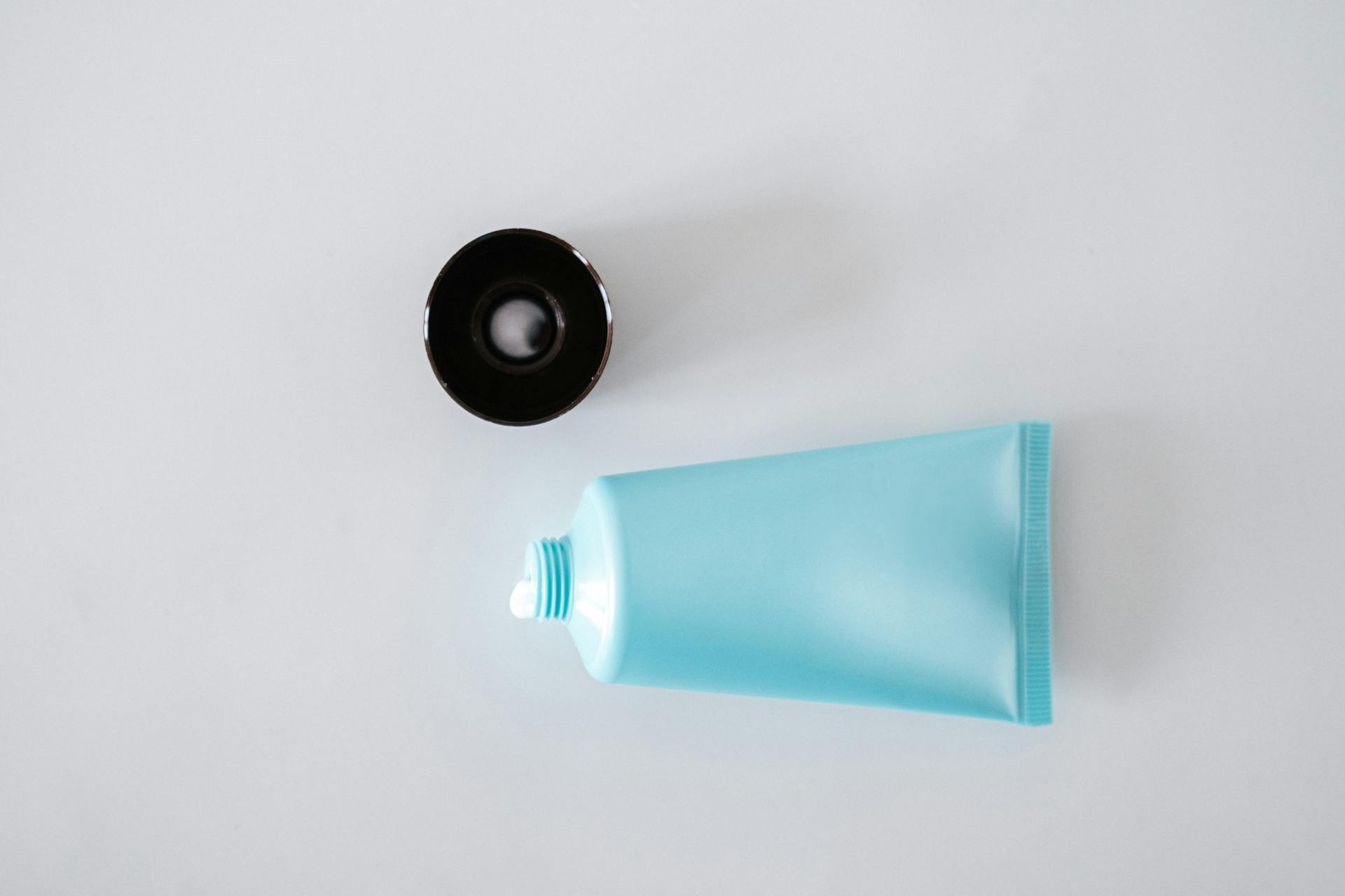 Top view of shiny tube of moisturizing cream with open plastic lid in daylight