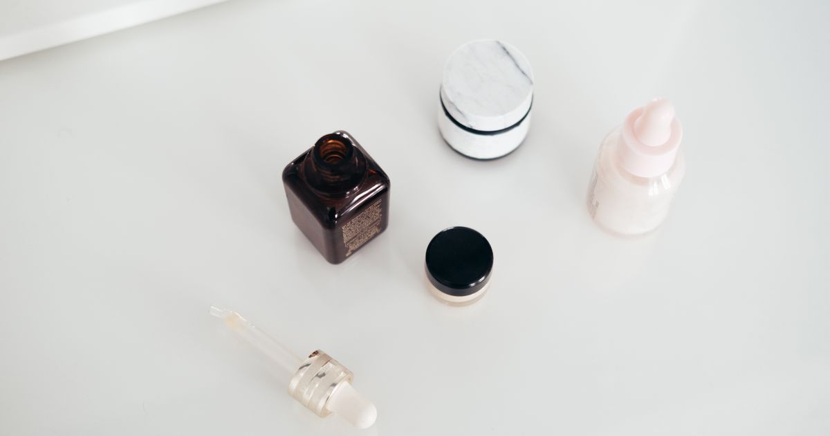 Skincare bottles, a serum dropper, and a cream jar arranged on a clean white table