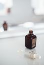 Small dark flacon of aroma oil near dropper on smooth table reflecting in mirror in daylight