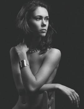 Elegant black and white portrait of a woman posing gracefully in a studio setting.