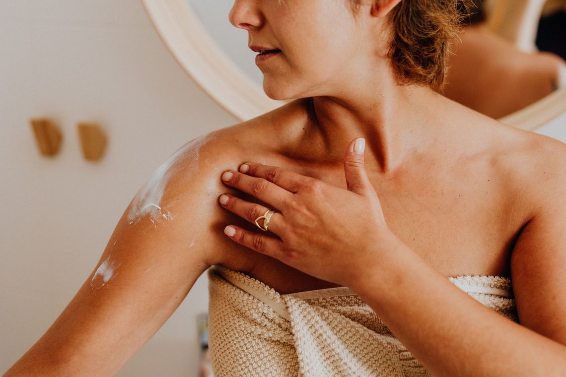 Woman applying body lotion to her shoulder