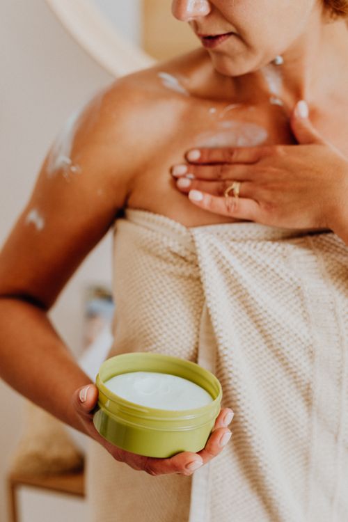 Free Close-up of woman applying body cream, enhancing skincare routine indoors. Stock Photo