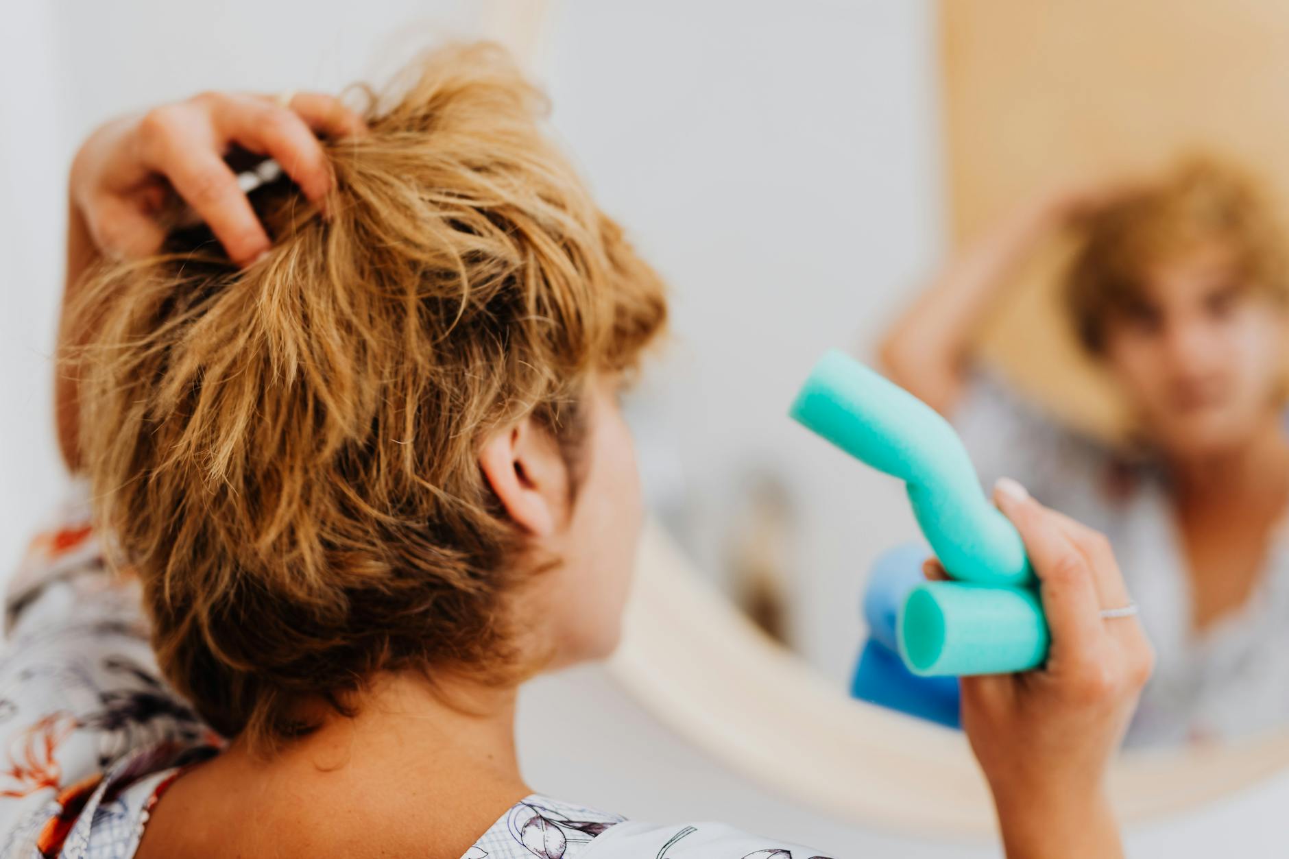 Featuring hair styling process - woman using blue curlers in front of a mirror for daily hair routine. for charlie's hair ...