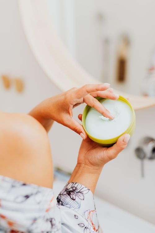 Free A woman applying skincare cream with fingers in a bathroom setting. Stock Photo