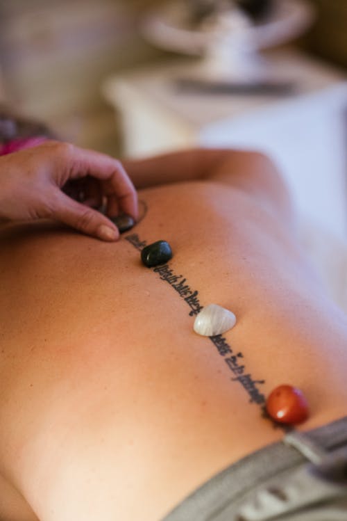Free Crop masseuse putting stones on back of client Stock Photo