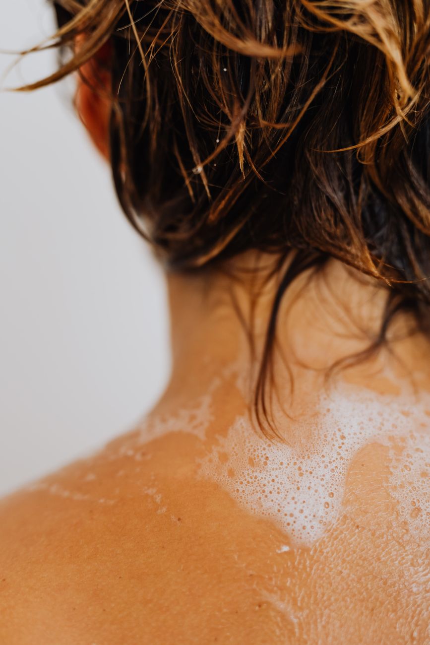 Soap, water and dark wet hair close to the scalp, where buildup and irritation become harder to romanticise.
