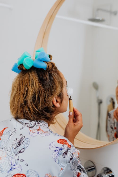 Woman Massaging Face in Front of Mirror