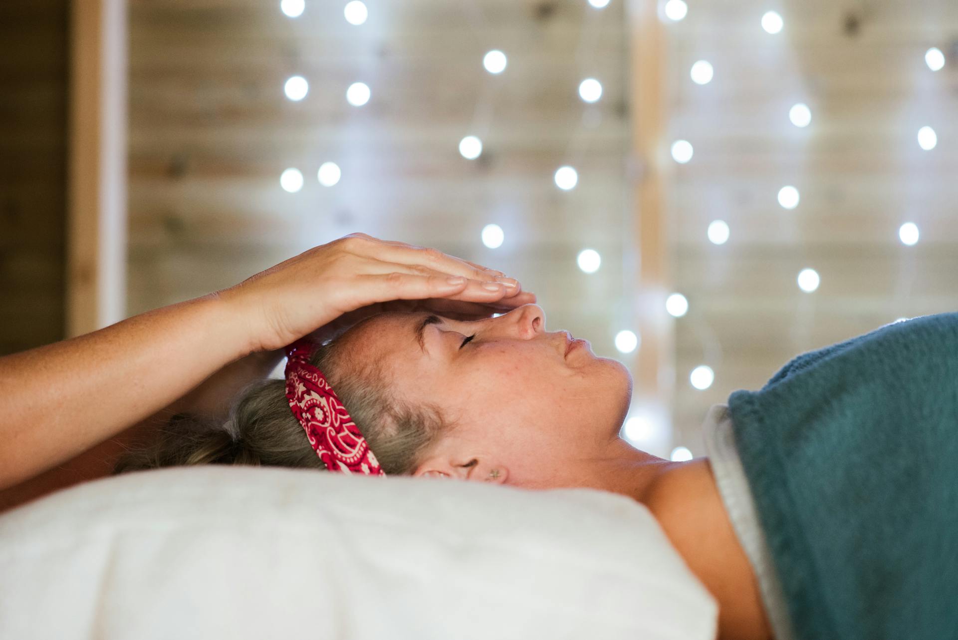 A serene spa therapy session with a woman relaxing and receiving a facial massage indoors.