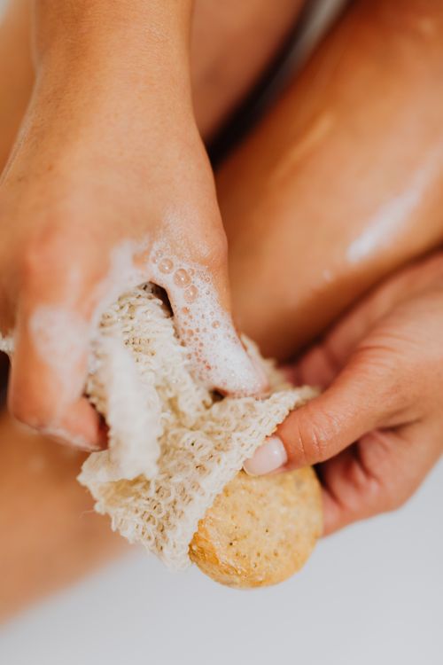 Free Close-up of a woman using a natural sponge and soap for exfoliation, embracing relaxation and body care. Stock Photo