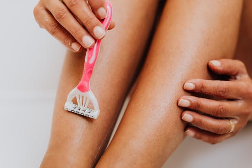 Free Person Using Shaver on Legs Stock Photo