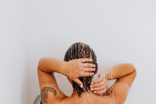 Free Woman enjoying a soothing shower with water cascading down, emphasizing relaxation and cleanliness. Stock Photo