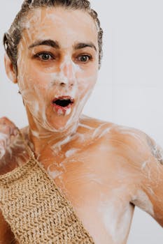 Woman bathing with soap and scrub, showcasing surprise and skincare routine.