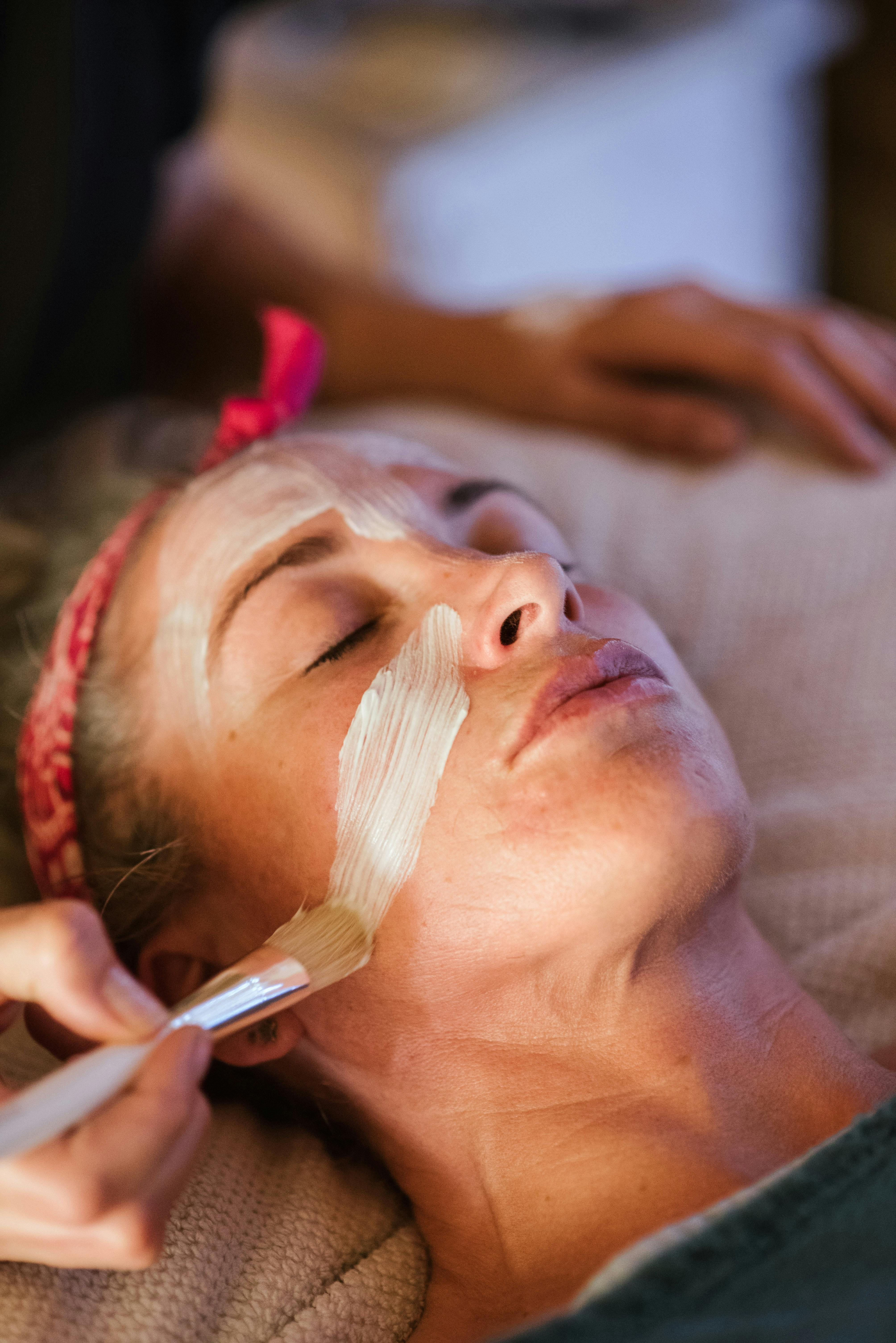 woman cleaning face with mask in spa center
