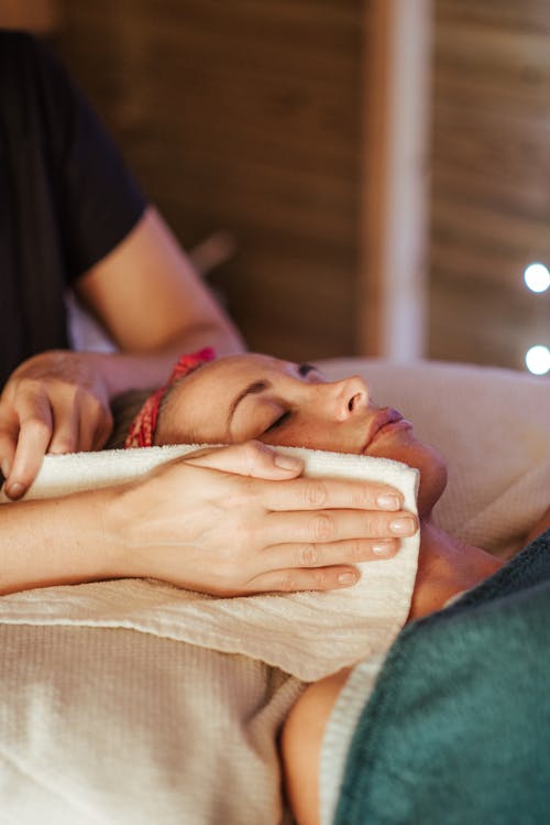 Free Adult lady lying in spa center while getting face massage from massager in spa salon Stock Photo