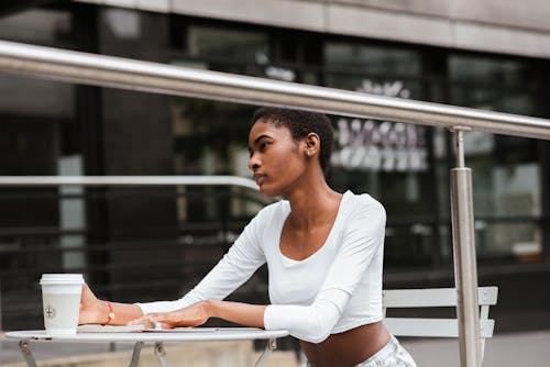 Femme Noire Expressive Assise Sur Une Terrasse Avec Café