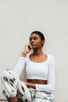 一位穿着时髦服装、留着短发的非裔美国女性神情严肃地坐着，手托下巴，面容难以看清